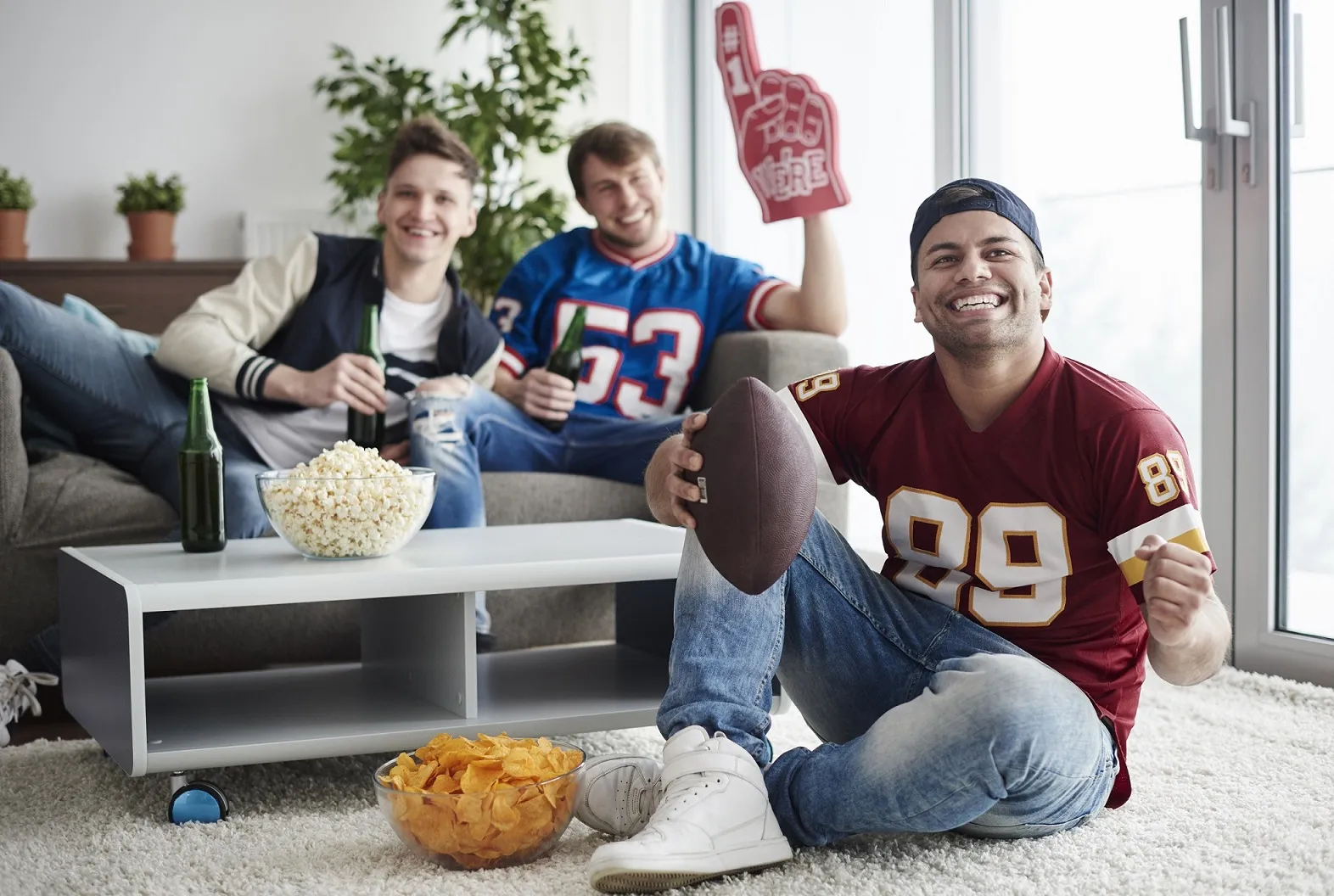 Amis regardant un match de sport avec Quebec IPTV, popcorn et ambiance festive à la maison