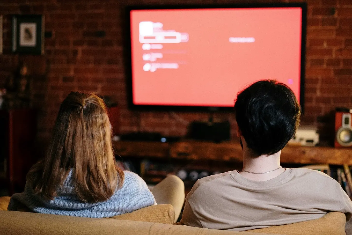 Activer IPTV sur television depuis le canapé avec un couple regardant une interface IPTV affichée sur un écran TV moderne dans un salon chaleureux.